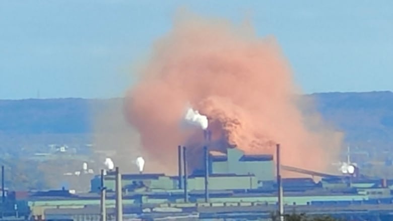 A red cloud comes out of a factory.