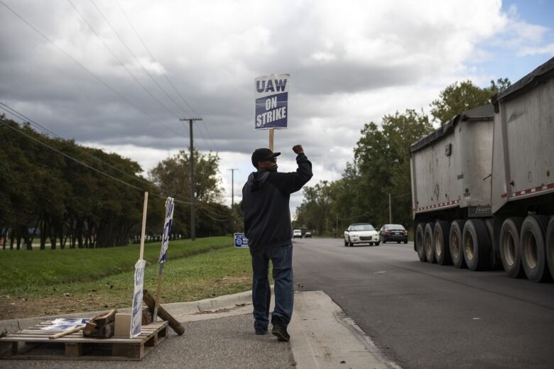 A demonstrator holds a sign during a United Auto Workers (UAW) strike outside the General Motors Co. (GM) plant in Romulus, Michigan,