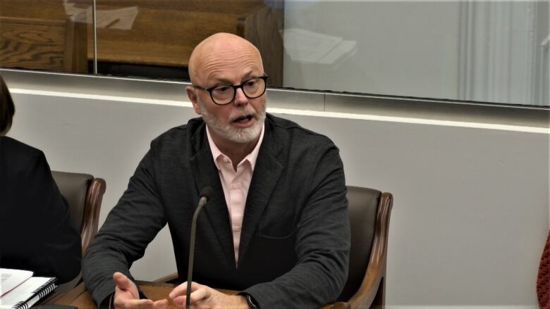 Dr. Michael Gardam, seated at a table, speaking into a microphone.