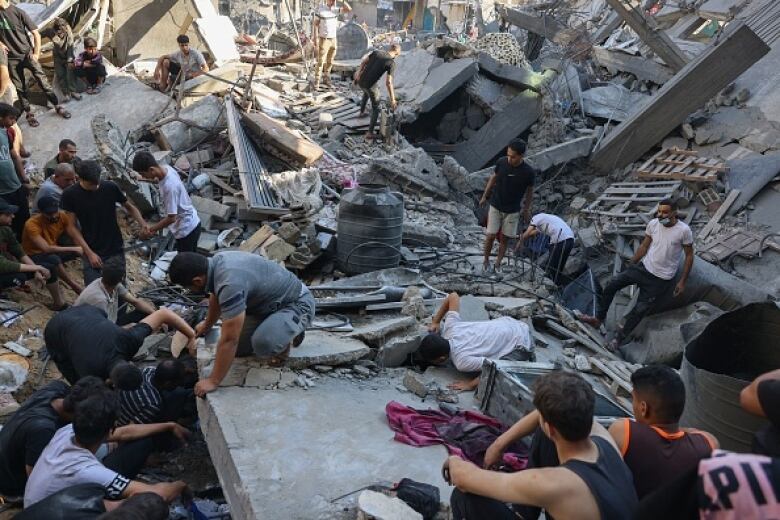 People search amid a ruined building for survivors.