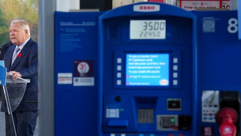 Ford speaks in front of a podium at a gas station.