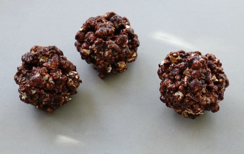 Three balls of popcorn coated in chocolate. 