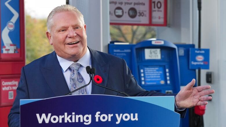 Premier Doug Ford stands in front of gas pumps, while speaking at a podium labelled 'Working For You.'  