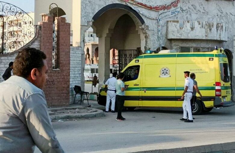 A yellow ambulance is shown at an entry way to a stone building, with several individuals shown standing near the vehicle.