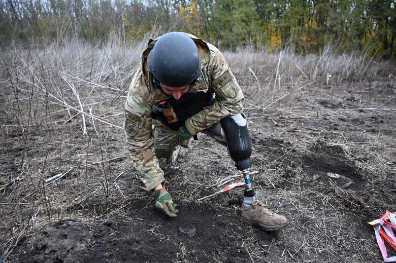 A Ukrainian police officer searches for mines in a field in the Izyum district last month.