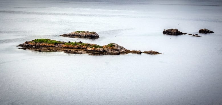 An aerial photo of a long, narrow island, with a handful of smaller islands in the waters nearby,