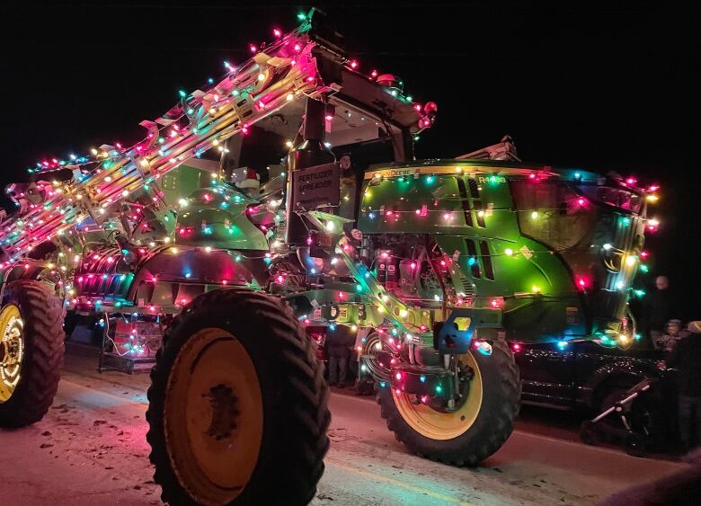 A tractor with strings of Christmas lights all over it