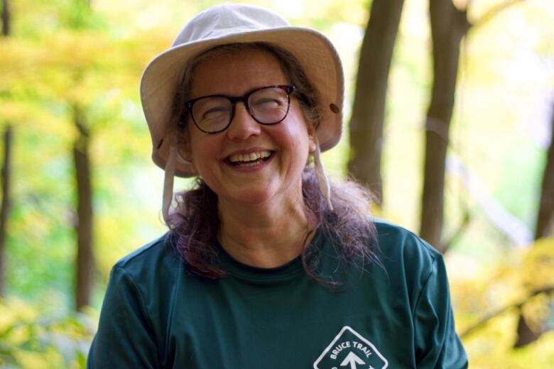 A portrait of a smiling person in a forested area. 