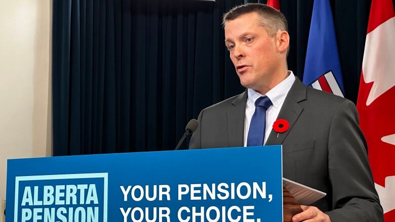 A man in a suit stands at a podium with 