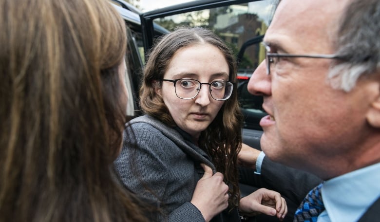 A woman looks around before getting into a car.