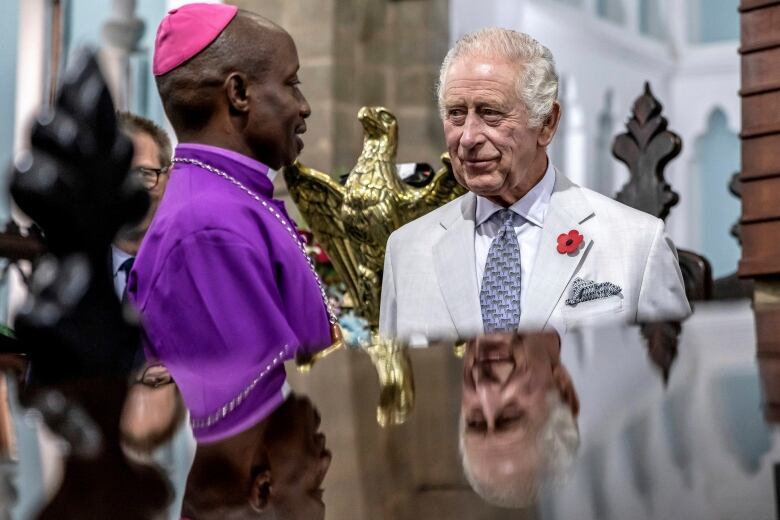 Two people speak to one another inside a church.