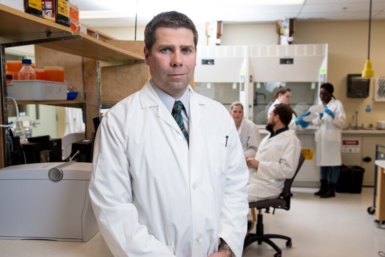 Scott Pavey stands in a lab coat in a university lab