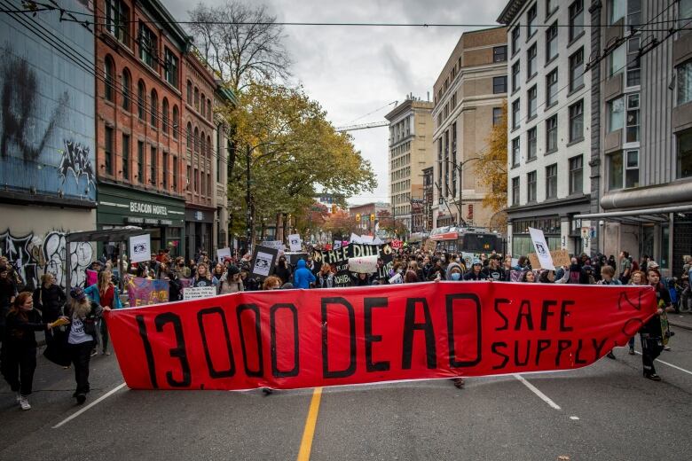 A crowd carries a large banner that says 