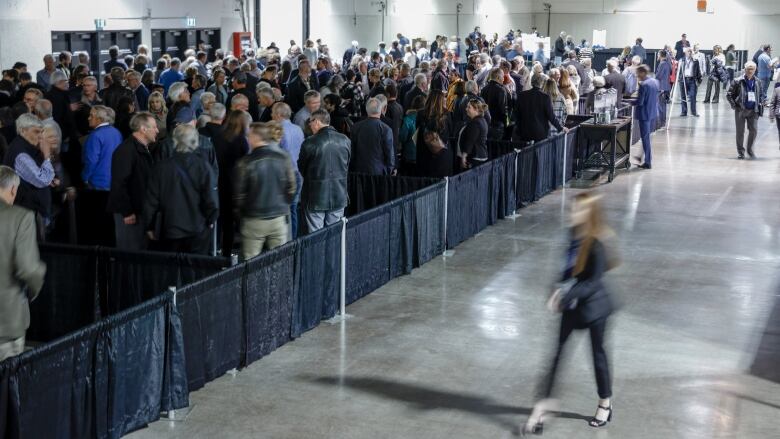 A crowd of people line up, waiting to enter a convention hall.