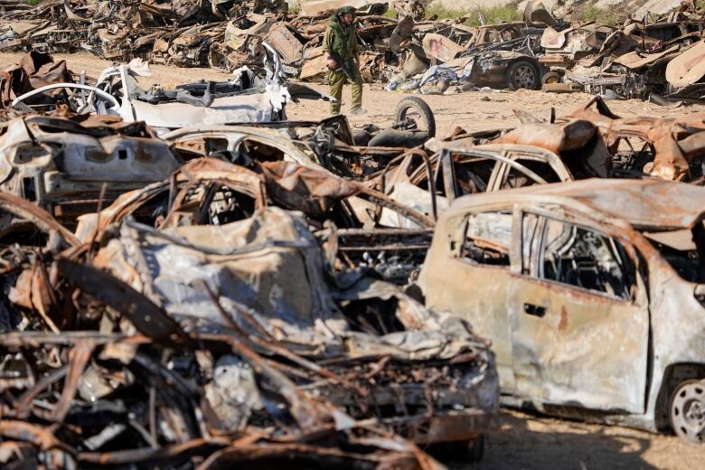 A solider inspects charred vehicles.