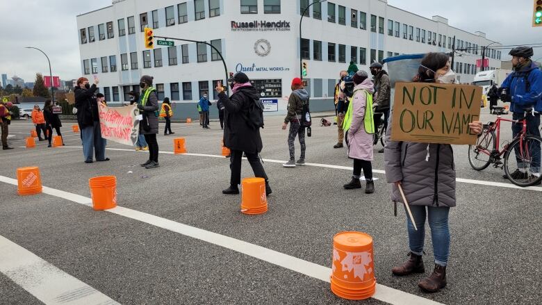 people block an intersection, one person holding a 