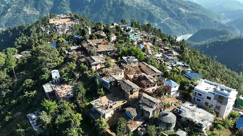 An aerial view shows damaged buildings atop a mountain.