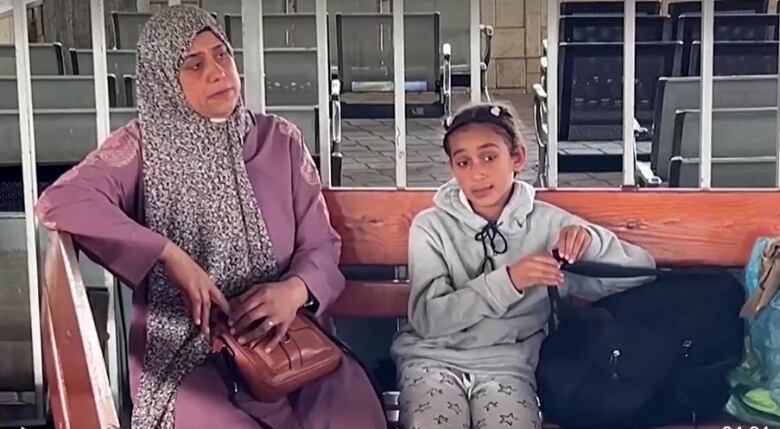 A woman and her daughter wait at a border crossing.