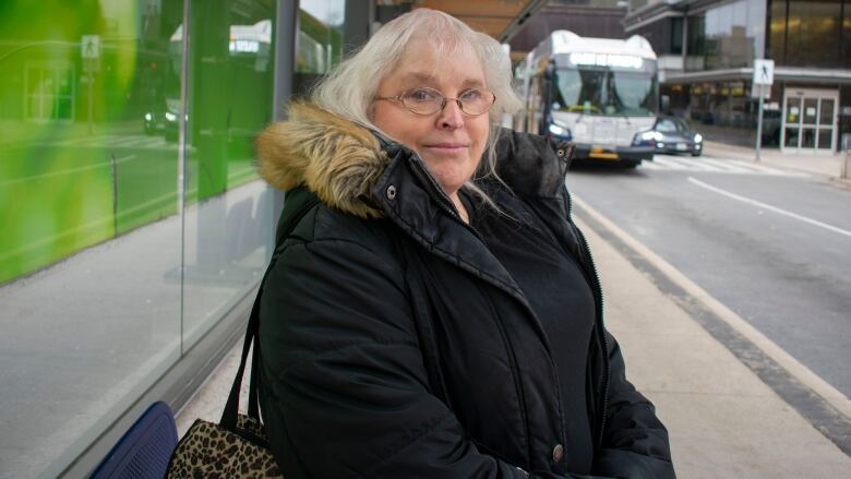 A woman standing at a bus terminal.