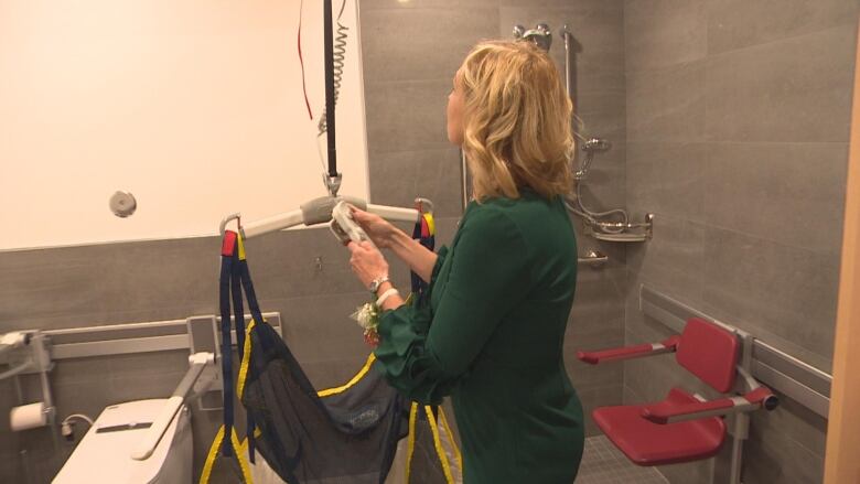 A woman in a green outfit presses a button that operates a hoist in a research lab.