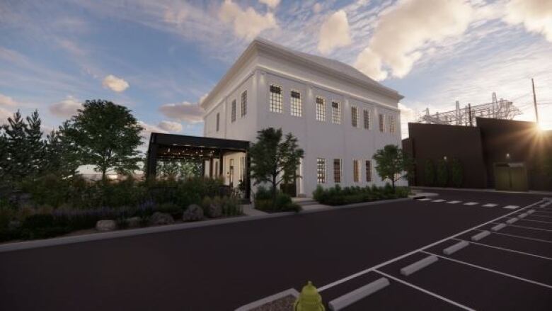 A white building in front of a parking lot with a patio beside it.