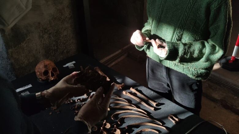 A person holds up old human bones.