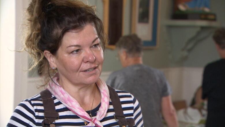 A woman wears a striped shirt and a pink bandana around her neck.