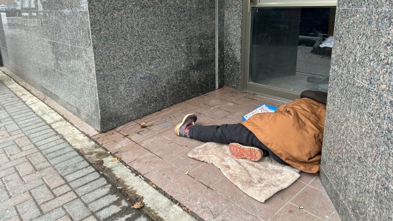 A person asleep outside a downtown storefront.