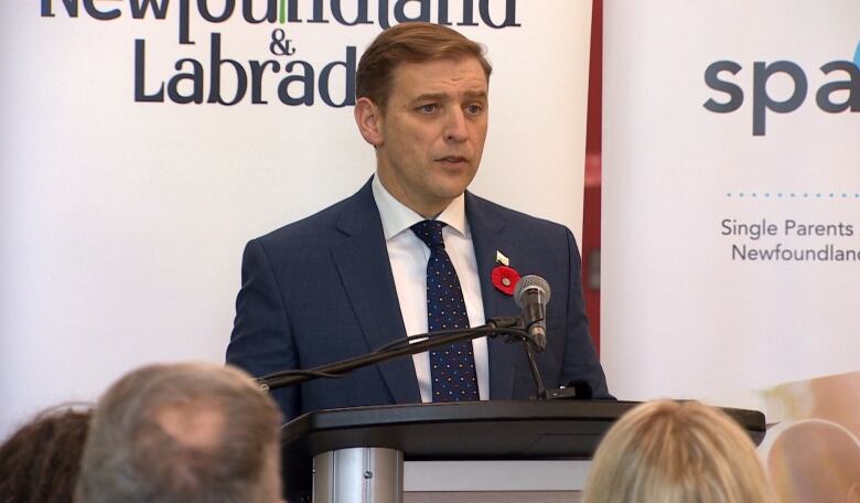 A man in a blue suit standing at a podium. 