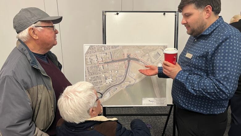 A man and a woman look at a map as a city official explains changes