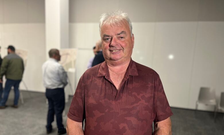 A man in a red shirt looks into the camera. 