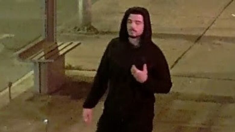 A man walking down a Toronto street, dressed in black.