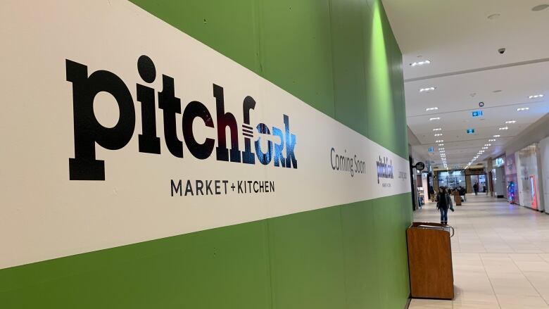 A wall with the Pitchfork Market and Kitchen logo inside a mall