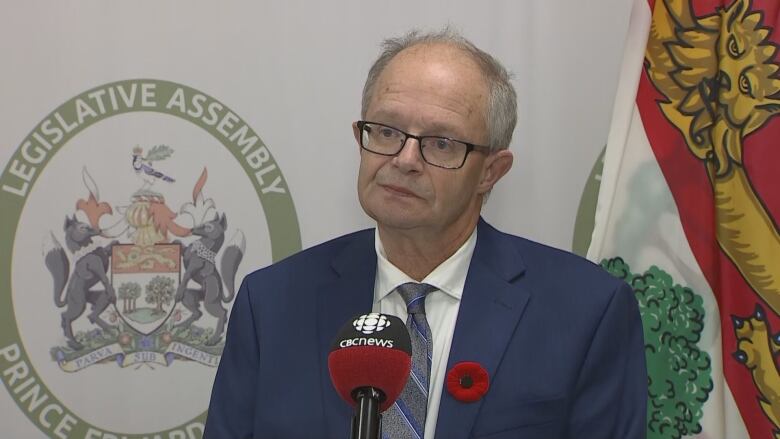 A man stands in front of a microphone waiting to answer a question from reporters.