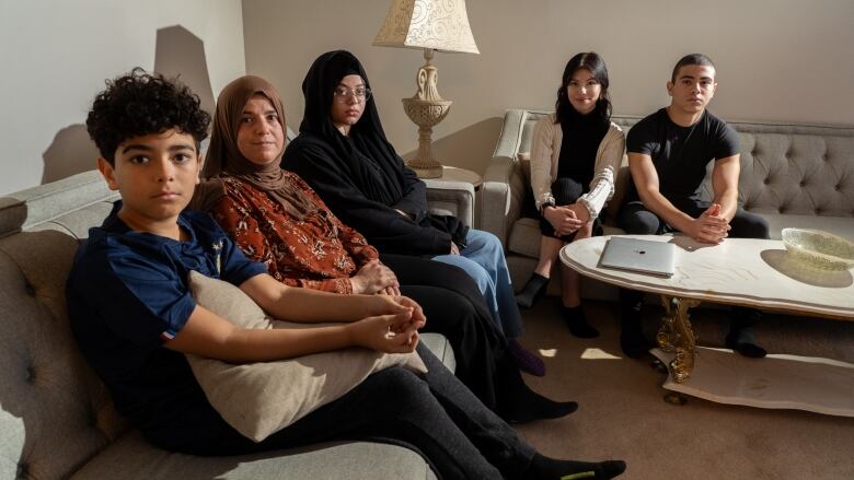 Five people sitting on couches in a living room.