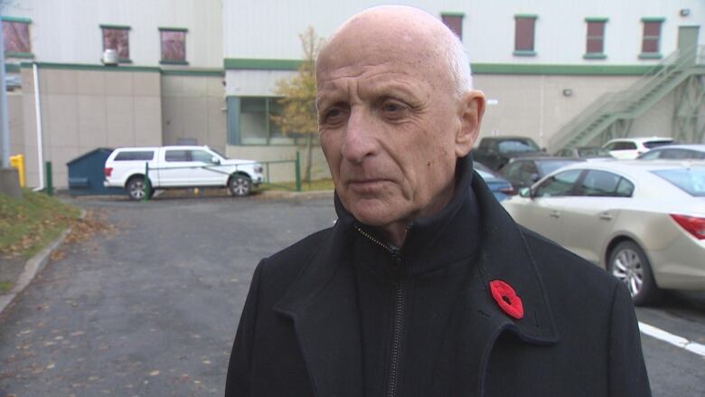 Man in dark coat with poppy pin on chest.