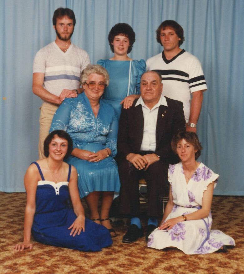 An old photograph of an elderly couple surrounded by five adults, their grown children.