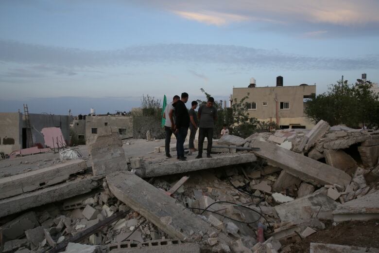 Men stand in the rubble of a home.