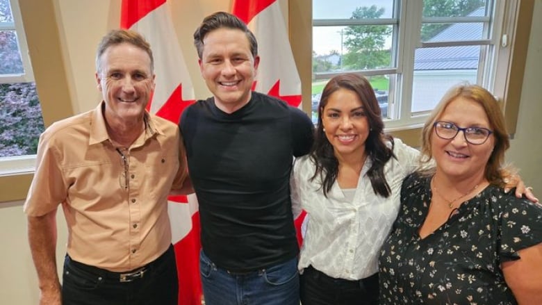 Two men and two women in casual clothing smile into the camera. 