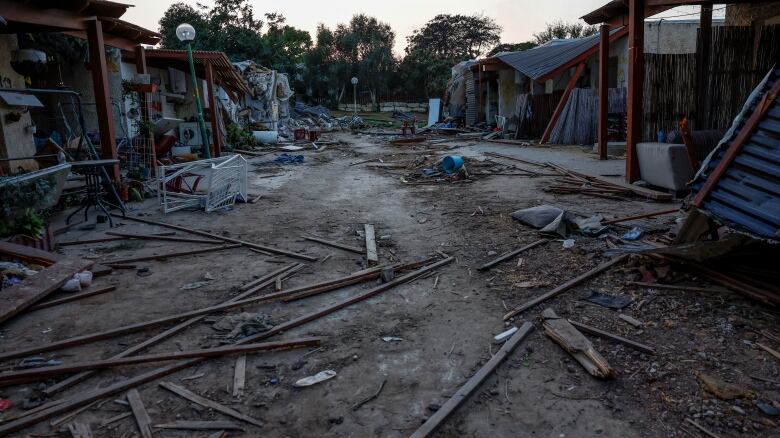 Destroyed buildings and pieces of debris are seen along a dirt path. 