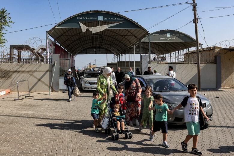 People and cars move through an open gate.