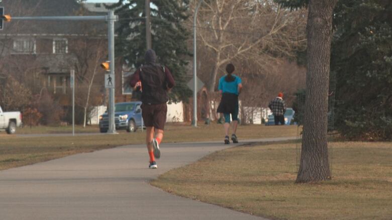 A man and a woman jog in a city park.