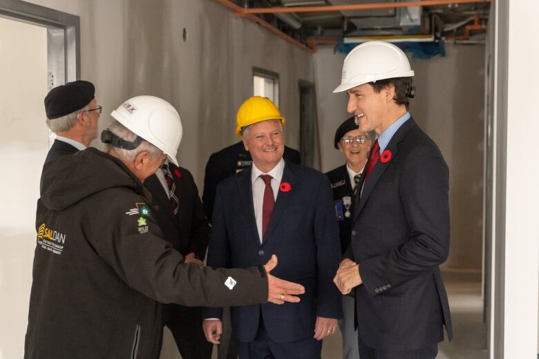 Prime Minister Justin Trudeau stands smiling in a housing development project in Sault Ste. Marie, Ont. with MP Terry Sheehan and other politicians.