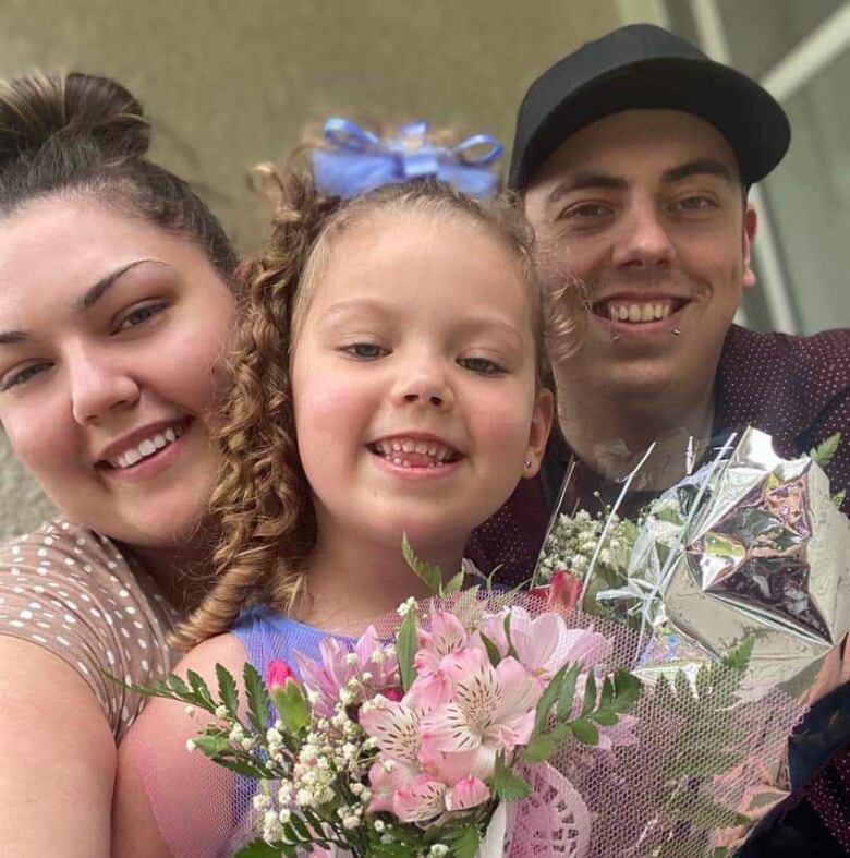 A family of three smile for a posed photo.