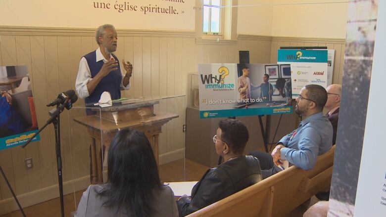 Dr. Haase stands in front of a group of people with examples of the billboards around him. 