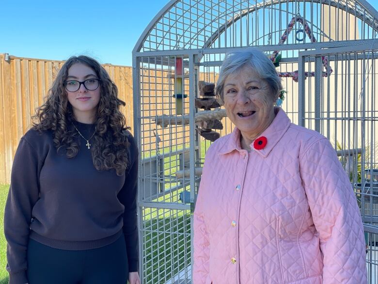 Two women stand near a bird cage