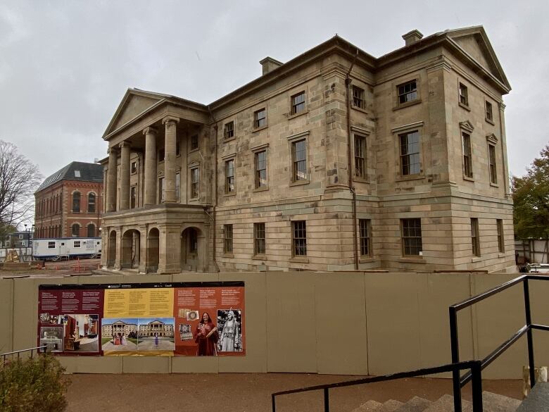 A stone building behind a construction barrier