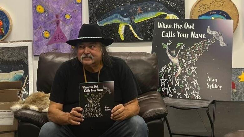 man sitting down holding his new book