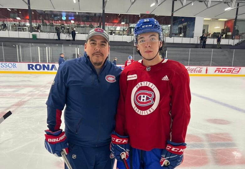 A Cree coach and a young Cree player in a Montreal Canadiens hockey jersey on the ice look at the camera. 