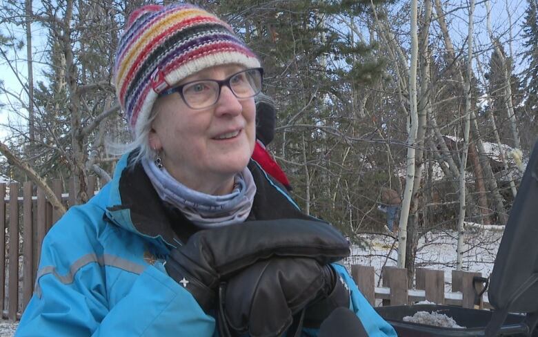 A woman in a toque and mitts stands outside.